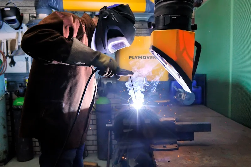 Operador realizando soldadura con sistema de ventilación industrial Plymovent Beckart en entorno seguro